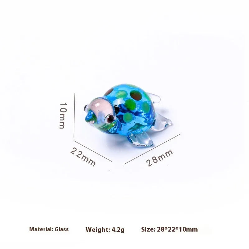 Geometric glass turtle ornament with a blue head and blue shell on a wooden desktop.