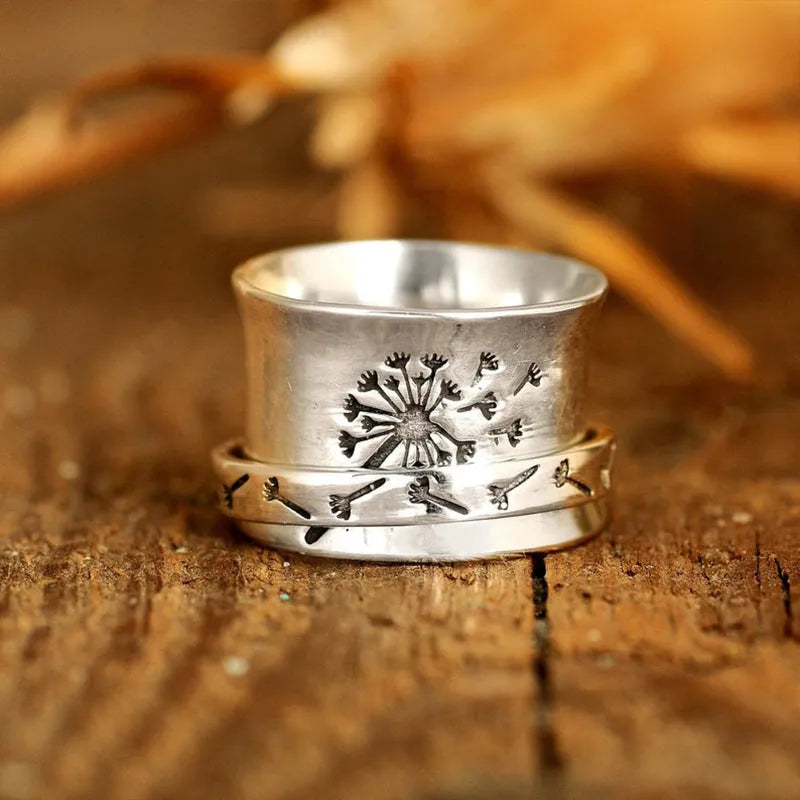 Silver-coloured rotatable flower ring on a finger, showing the floral detail.