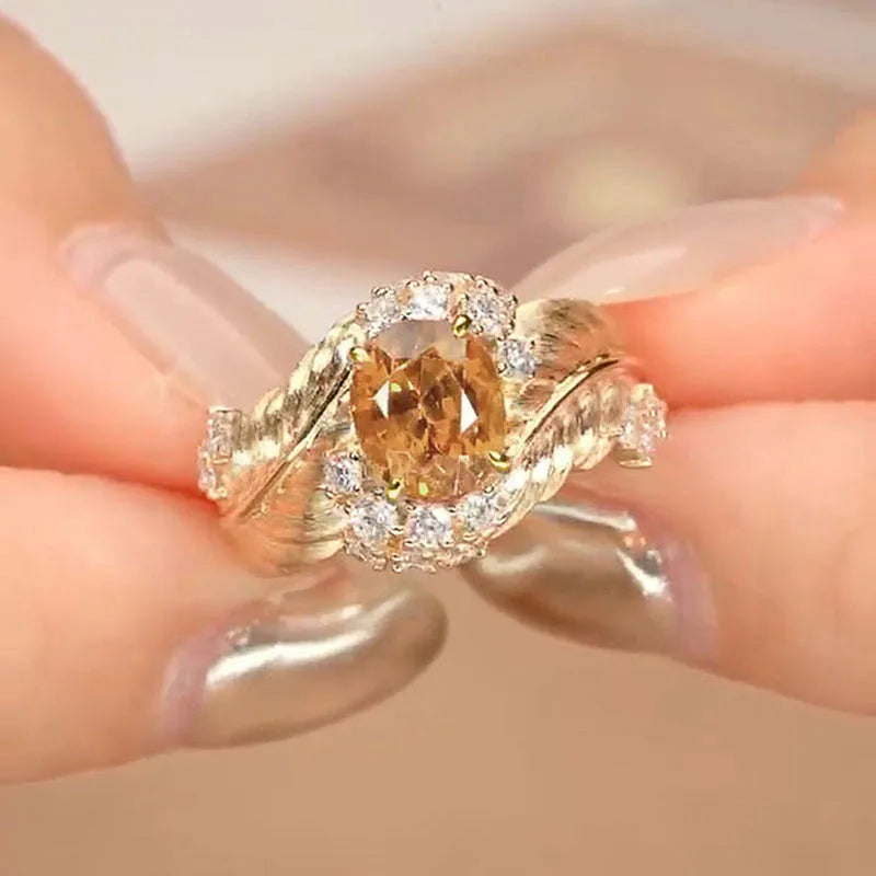 Gold-toned copper ring with embossed feather pattern and a central yellow zircon stone on a geometric band.