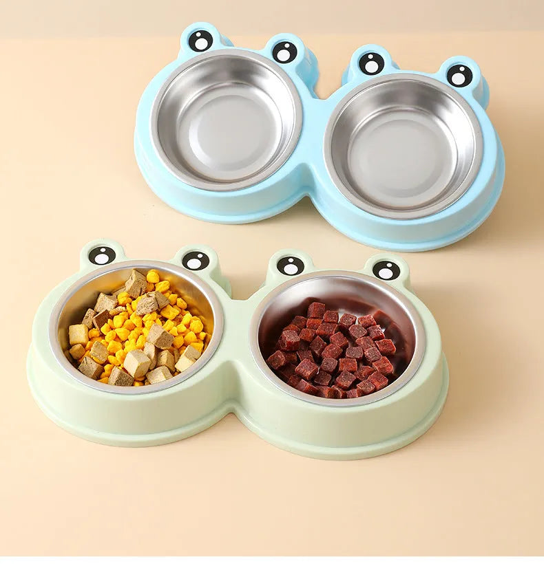 Frog-shaped plastic holder containing two stainless steel pet bowls for food and water.