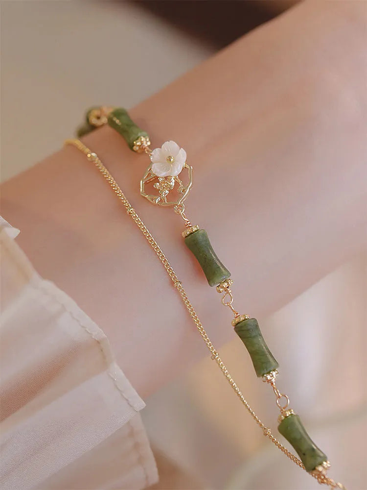 Natural olivine gemstone bracelet with double layers and twin Bells of Ireland charms on a wrist.