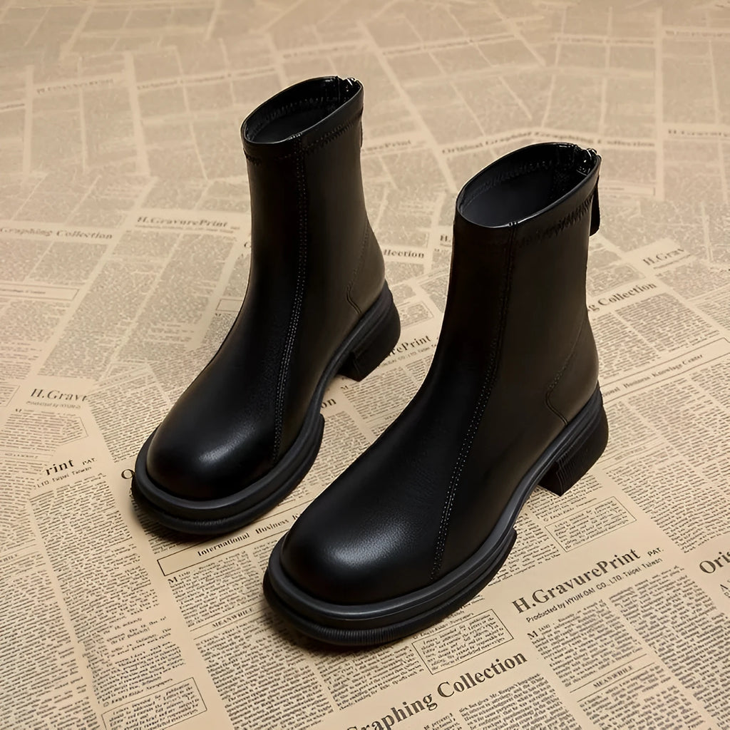 Women's black ankle boots with a flat thick heel, round toe, and a back zipper closure.